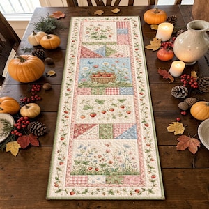 May include: A rectangular quilted table runner featuring a patchwork design with strawberry plants, a basket of strawberries, and floral motifs in shades of pink, blue, and green, bordered by a vine pattern with small red strawberries throughout.