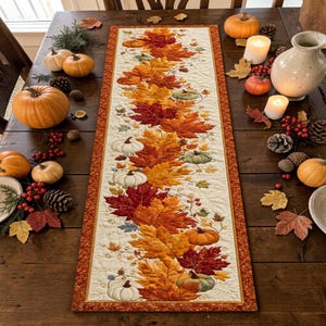 May include: A rectangular quilted table runner featuring a central vertical pattern of vibrant autumn leaves in shades of orange, red, and yellow, interspersed with small white and green pumpkins, all bordered by a dark orange fabric trim.