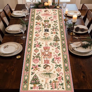 May include: A rectangular table runner featuring a repeating Christmas pattern of ballerinas, nutcrackers, decorated trees, candy canes, and ornaments in shades of pink, green, and cream, bordered by a green and pink floral garland design.