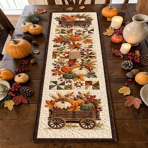 May include: A rectangular fabric table runner featuring a quilted design with autumn motifs, including wooden wagons filled with pumpkins, gourds, and fall leaves. The runner has a cream-colored background with intricate swirling stitching patterns.