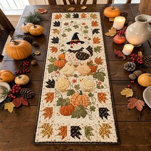 May include: A rectangular fabric table runner featuring a quilted design with a central applique of a chicken wearing a witch hat, surrounded by small chicks, pumpkins, and autumn leaves in shades of orange, brown, and green on a cream background.