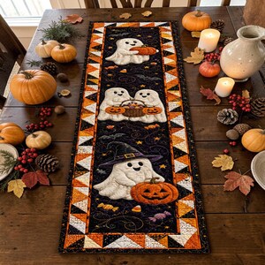 May include: A rectangular quilted table runner featuring a black background with a pattern of white ghosts, orange pumpkins, and candy. The border consists of a geometric triangle pattern in orange, black, and white. The runner is centered on a wooden table.