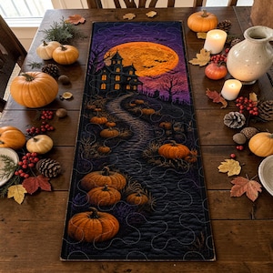 May include: A rectangular quilted table runner featuring a dark Halloween scene with a haunted house, a large orange full moon, and a winding path lined with orange pumpkins. The fabric displays a purple and black sky with silhouettes of bats.