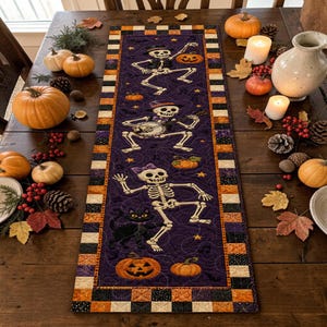 May include: A rectangular table runner featuring a purple background with a quilted pattern of three dancing skeletons, a black cat, and orange pumpkins. The border consists of a black, white, and orange checkered design with small stars.