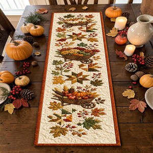 Peut inclure: Un chemin de table matelassé rectangulaire présentant un motif répétitif de brouettes en bois remplies de citrouilles, de courges et de feuilles d'automne, agrémenté d'étoiles et de feuillages aux tons orange, jaune, vert et marron.
