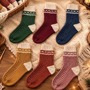 Peut inclure: Six paires de chaussettes en tricot vert, rouge foncé, bleu marine, jaune moutarde, orange rouille et rose poudré. Chaque chaussette présente un motif gaufré texturé, un revers côtelé crème avec un petit motif de cœur et un talon crème.