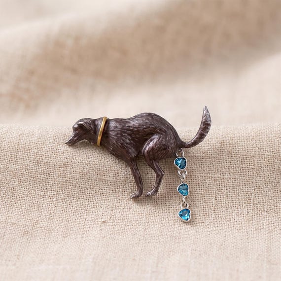 A handmade brooch shaped like a little dog poop emoji — silly, sculptural, and the kind of lapel pin that stops people mid-conversation.