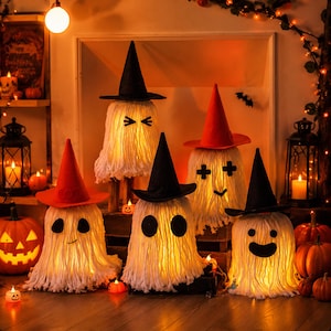 Puede incluir: Cinco decoraciones de fantasmas iluminadas hechas de cabezas de fregona blancas, cada una con un sombrero de bruja puntiagudo negro o naranja. Los fantasmas presentan varias expresiones faciales de fieltro negro y están iluminados.