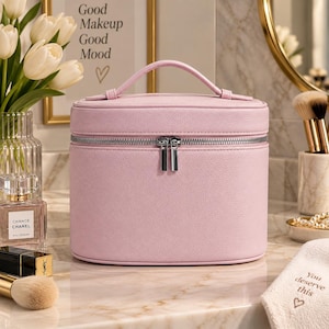 Peut inclure: Une trousse de toilette ovale rose clair avec un extérieur texturé, une poignée supérieure et une fermeture éclair double argentée. Ce vanity structuré présente un design épuré avec une base plate et un couvercle zippé sécurisé.