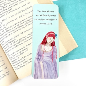 May include: A bookmark featuring a watercolour illustration of a woman with long red hair and a purple dress. The background is a light blue colour. The bookmark includes the quote "Your time will come. You will face the same Evil, and you will defeat it. -Arwen, LOTR".