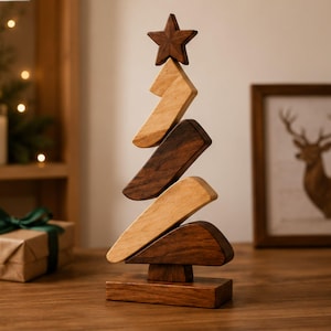 Peut inclure: Une sculpture décorative en forme de sapin de Noël composée de segments de bois alternant entre des tons clairs et foncés. L'arbre est surmonté d'une étoile et repose sur une base rectangulaire en bois, avec un design géométrique empilé.