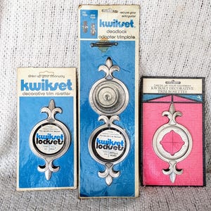 May include: Three packages of Kwikset decorative trim rosettes. The packages are blue, pink, and white with silver trim. Each package features a different design of the rosette.