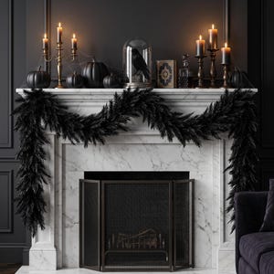 May include: A white marble fireplace mantel draped with a thick black feather garland. The mantel features black pumpkins, a gold candelabra with lit candles, a black bird inside a glass cloche, a decorative book, a glass decanter, and pillar candles.