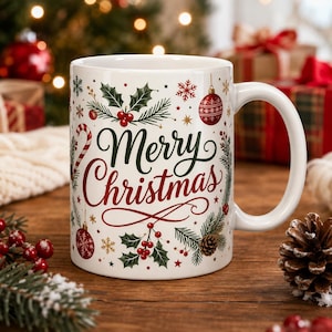 May include: A white ceramic mug featuring the text Merry Christmas in green and red script. The design includes illustrations of red ornaments, green holly leaves with red berries, pine branches, pinecones, snowflakes, and a candy cane.