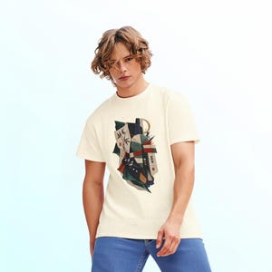 May include: A cream-colored short-sleeve t-shirt featuring a central graphic print with abstract shapes, bamboo stalks, and Japanese characters. The shirt is paired with blue denim jeans, creating a casual look with a crew neckline and a straight hem.