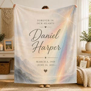Könnte beinhalten: Eine weiche Fleecedecke mit einem Berglandschaftsdruck unter einem Himmel mit Regenbogen und strahlender Sonne. Der Text lautet FOREVER IN OUR HEARTS, Daniel Harper, und MARCH 8, 1959 - JUNE 14, 2025, verziert mit kleinen Herz- und Sternsymbolen.