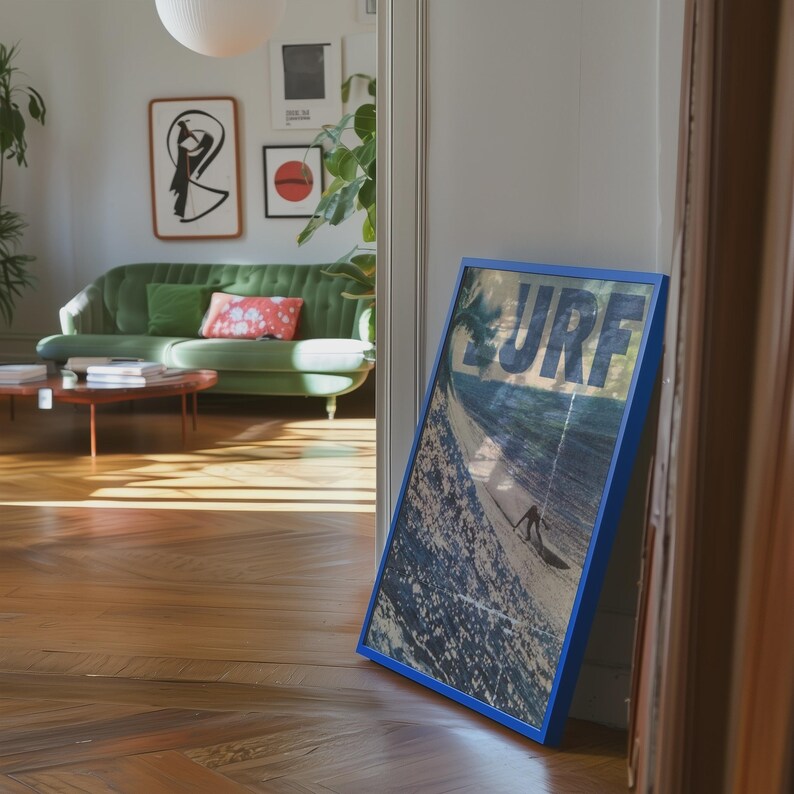 May include: A rectangular framed print featuring a blue border and a vintage-style graphic of a surfer on a wave with the word SURF printed in large, bold, white letters across the top portion of the image, leaning against a door frame.