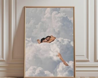 May include: A framed wall art print featuring a surreal collage of two figures embracing and kissing while partially submerged within a dense, voluminous expanse of white and grey cumulus clouds against a soft, pale blue sky background.