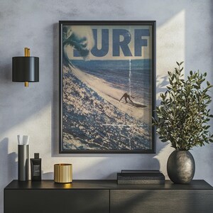 May include: A framed wall art print featuring a vintage-style ocean scene with a large breaking wave and a surfer. The word SURF is printed in large blue letters across the top. The image has a distressed texture with vertical lines.