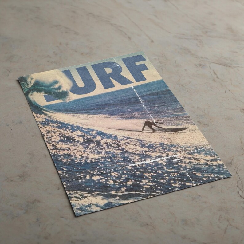 May include: A rectangular print featuring a blue ocean wave and a surfer on a board. The word SURF is printed in large, bold, blue capital letters across the top. The image displays a textured, weathered appearance with a visible vertical crease.