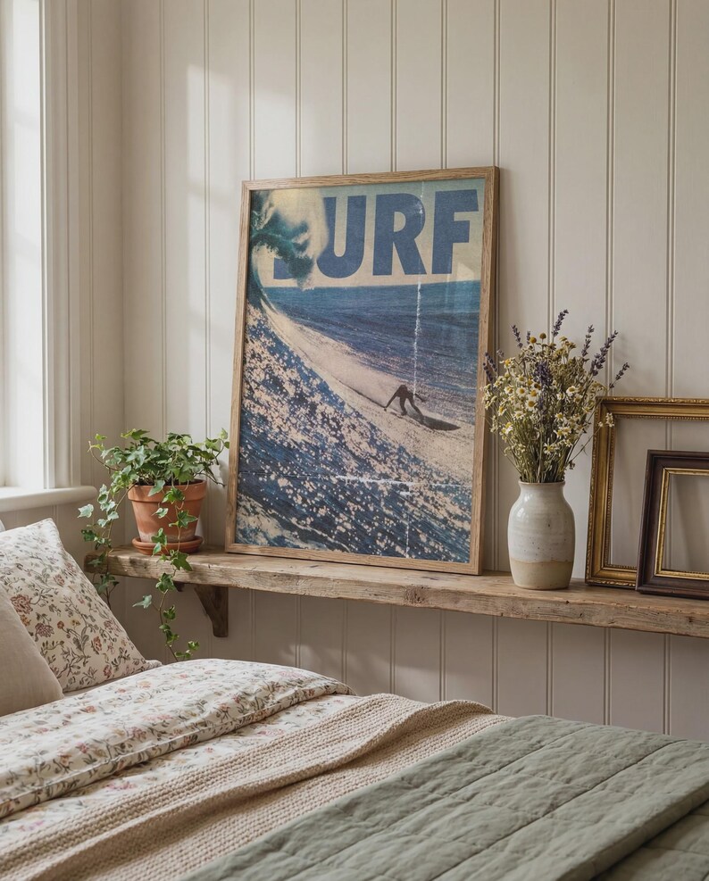 May include: A rectangular framed wall art print featuring a blue ocean wave and a surfer with the text URF in large blue letters at the top. The print is displayed in a light wood frame, showcasing a dynamic scene of a person surfing a wave.