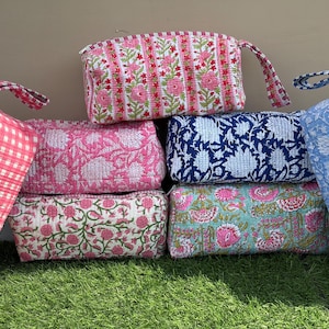 May include: A collection of six rectangular quilted pouches featuring various floral and gingham patterns in shades of pink, blue, white, and green. Each pouch includes a matching fabric handle attached to the side, with visible stitching.