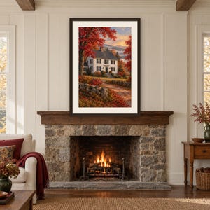 May include: A framed wall art print depicting a white two-story house with black shutters, surrounded by vibrant red autumn trees and a stone wall, set against a sunset sky, displayed above a stone fireplace with a burning fire inside.