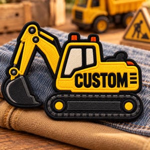 May include: An embroidered patch shaped like a yellow and black excavator construction vehicle. The design features a long articulated arm with a dark gray bucket, a cab with white windows, and black tracks. The word CUSTOM is stitched in black.