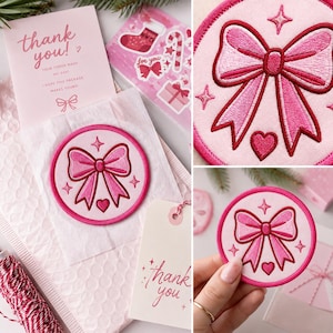 May include: A circular embroidered patch featuring a pink bow, a small heart, and four-pointed star accents. The patch has a dark pink stitched border and is presented with a thank you card and a sheet of holiday-themed stickers.