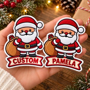 May include: Two embroidered patches featuring a cartoon Santa Claus wearing a red suit, black belt with a gold buckle, and a white-trimmed hat. Each Santa carries a brown sack. Below each figure is a banner with the text CUSTOM and PAMELA.