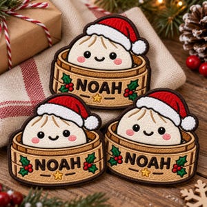May include: Three embroidered patches featuring a smiling dumpling character wearing a red and white Santa hat, sitting inside a bamboo steamer basket. The basket is decorated with holly leaves, red berries, a yellow star, and the name NOAH.