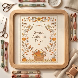 Könnte beinhalten: Ein quadratischer Holzrahmen mit einem Kreuzstichmuster und dem Text Sweet Autumn Days, umgeben von gestickten Kürbissen, Vögeln und Laub. Das Stück ist mit verschiedenen Stickgarnsträngen und einer Metallschere arrangiert.
