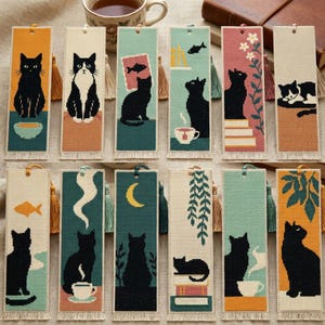May include: Twelve rectangular cross-stitch bookmarks featuring various cat illustrations, including black and tuxedo cats, tea cups, fish, moons, and plants. Each bookmark has a fabric texture, a top hanging loop with a tassel, and a fringed bottom edge.