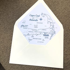 May include: A cream-colored envelope with an open flap revealing a printed liner featuring a blue map of Cape Cod and Islands. The map includes text labels for towns like Sandwich, Barnstable, and Chatham, along with illustrations of a lighthouse, a sailboat, and a whale tail.