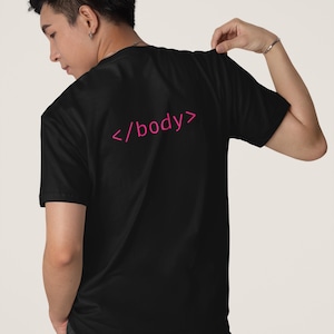 Op de afbeelding: Een zwart t-shirt met korte mouwen en de tekst </body> in een felroze kleur op de achterkant. Het shirt heeft een ronde hals en een standaard pasvorm, wat zorgt voor een strakke uitstraling voor dagelijks gebruik met een programmeer-thema.