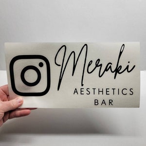 Puede incluir: Logotipo de Instagram en blanco y negro con el texto "Meraki Aesthetics Bar" debajo.