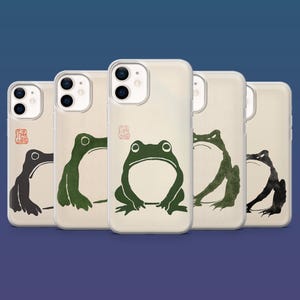 Könnte beinhalten: Fünf transparente Smartphone-Hüllen in einer Reihe, jede mit einer individuellen Tusche-Illustration eines Frosches in verschiedenen Grün-, Schwarz- und Grautönen. Jede Hülle hat ein kleines rotes quadratisches Stempelmotiv oben links.