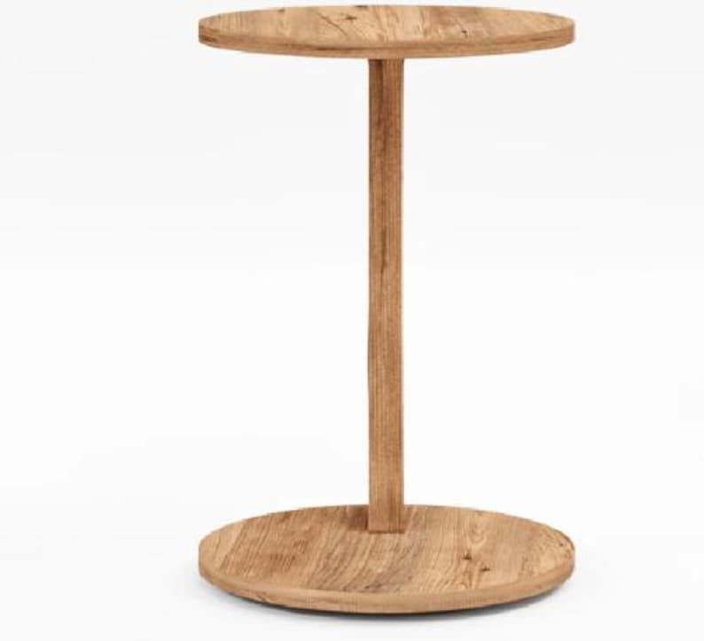 Pu&ograve; includere: Un tavolino rotondo con finitura in venature di legno marrone chiaro. Il tavolo presenta un piano circolare sostenuto da un unico montante centrale verticale che si collega a una base circolare abbinata, creando un mobile semplice e funzionale.