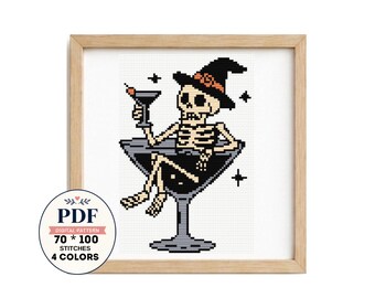 Puede incluir: Un patrón de punto de cruz con un esqueleto que lleva un sombrero de bruja negro con una banda naranja, sentado dentro de una copa de martini grande y sosteniendo una copa de cóctel. Incluye estrellas y el texto PDF 70 * 100 STITCHES 4 COLORS.
