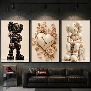 May include: A triptych wall art set featuring a black character figure with gold accents on the left, a central white heart with gold cracks and pink roses, and a white character figure sitting on a marble block on the right, all with floral details.