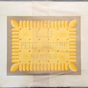 Peut inclure: Une impression graphique rectangulaire jaune représentant un biscuit avec des bords festonnés et des coins arrondis. Le texte LU, PETIT-BEURRE et NANTES est embossé au centre, entouré de petites indentations circulaires sur un fond clair.
