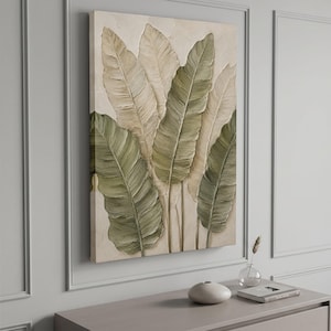 May include: A rectangular canvas wall art piece featuring a textured, layered depiction of large tropical leaves in shades of sage green, olive, and cream. The artwork displays thick, visible brushstrokes and a raised impasto surface finish.