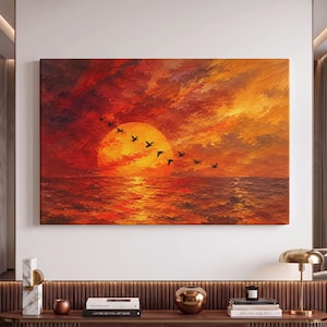 May include: A rectangular canvas wall art piece featuring an oil painting of a vibrant sunset over the ocean. The scene displays a large, glowing orange sun partially obscured by a flock of black birds flying in a diagonal formation across the sky.