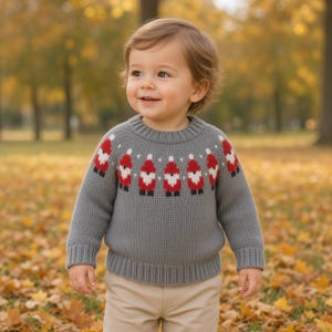 Könnte beinhalten: Ein grauer, langärmeliger Strickpullover mit einem wiederkehrenden Muster aus kleinen roten und weißen Gnomen um den Halsausschnitt. Der Pullover hat einen gerippten Rundhalsausschnitt, Bündchen und Saum und wird mit einer hellbeigen Hose getragen.