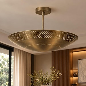 May include: A wide, bowl-shaped ceiling light fixture with a brushed brass finish. The metal shade features a perforated pattern of small, evenly spaced holes along its outer edge, suspended from the ceiling by a central rod and a circular canopy.
