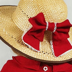 May include: A straw hat with a wide brim and a red bow with white lace trim. The hat is brown and has a woven texture.