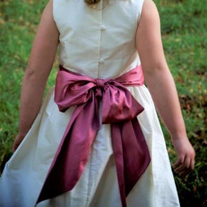 Flower girl dress pdf sewing pattern, cummerbund sash, big bow, classic flower girl frock, pink sash, cream bodice, covered buttons, rouleaux loop fastening. Free You Tube Video playlist. Back view of the handcovered cover buttons.