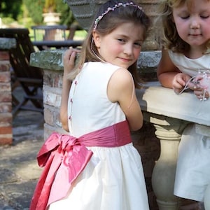 Flower girl dress pdf sewing pattern, cummerbund sash, big bow, classic flower girl frock, pink sash, cream bodice, covered buttons, rouleaux loop fastening. Free You Tube Video playlist. Back view of the handcovered cover buttons.