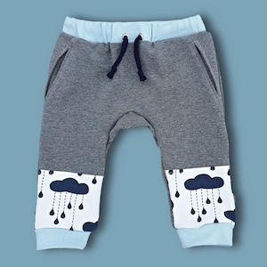 May include: Gray sweatpants with a blue waistband and blue cloud print on the legs. The clouds have raindrops hanging from them.