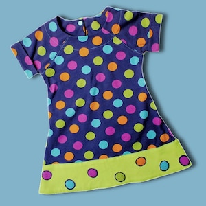 May include: A blue polka dot dress with a green trim and colorful polka dots. The dress has short sleeves and a round neckline.